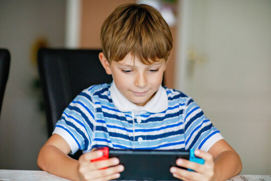 Little Boy playing a handheld video game console at home, focused on digital entertainment and interactive gaming during leisure time