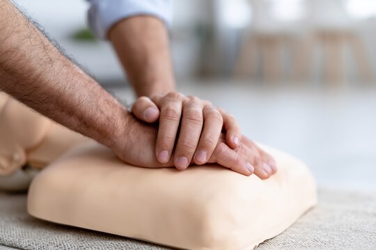 Close up of hands performing cpr compressions on a medical training mannequin for emergency first aid certification