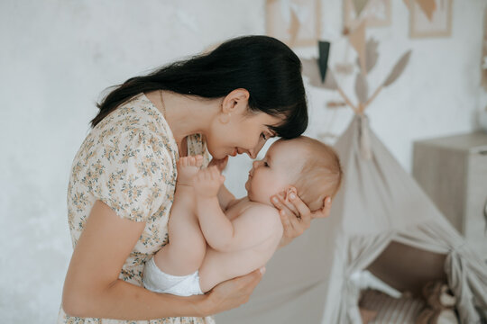Mother and baby, a mother with her baby at home, maternal love and care, a mother gently hugs and kisses her little child, space for text.