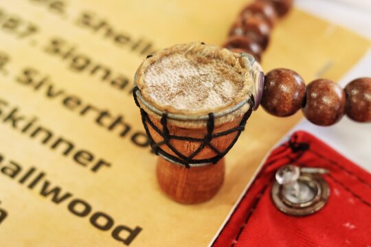 Editorial photo of a close-up shot of a miniature decorative djembe drum souvenir alongside wooden beads and documents displayed at the Emancipation Village festival.