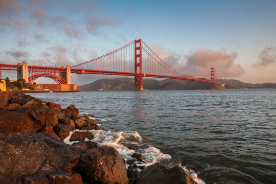 Beautiful Golden Gate Bridge and Fort Point at sunrise with rocky shore