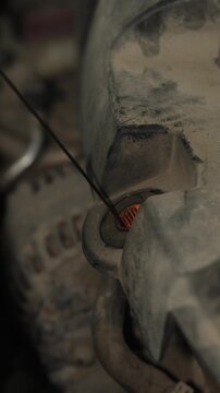 Pulling out the oil dipstick from a dusty engine bay.