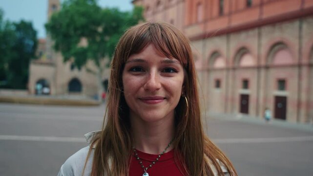 Portrait nice Caucasian young girl smiling looking happy at camera urban day outdoors. Generation z friendly only brown or redhead woman posing cheerful in street city background. 