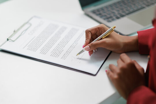 Professional woman signing a business agreement, formalizing a legal contract with a pen on an official document, symbolizing important partnership and commitment