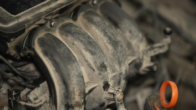 Dusty plastic intake manifold inside a car engine bay area.