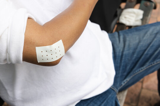 elbow closeup of asian senior man with tennis elbow and pain relieving patch on the arm, injury treatment concept, high angle view