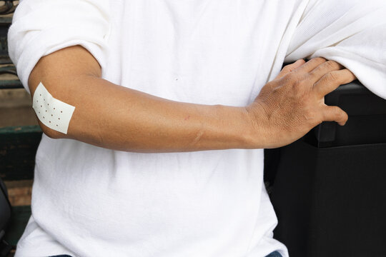 elderly asian man wearing a pain relief patch on his elbow for tennis elbow, front view close up medical shot