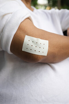 senior asian male elbow with adhesive pain patch for tendonitis and inflammation, side view closeup medical photography in natural light