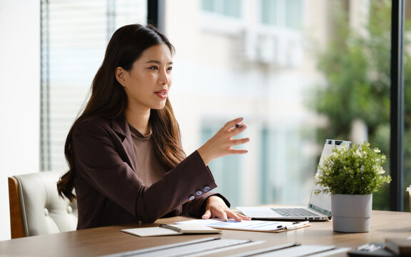 Professional businesswoman presenting ideas while reviewing financial charts and reports during a meeting in a modern office.
