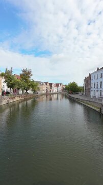 Vertical panning view over stone bridge crossing canal in Bruges, Belgium