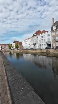 Vertical panning view over canal showcasing traditional architecture in historic center of Bruges, Belgium, morning light