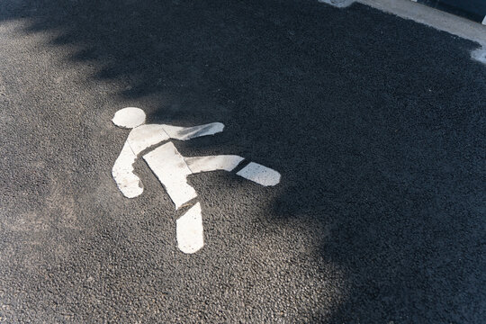 Pedestrian crossing symbol painted on asphalt road surface.