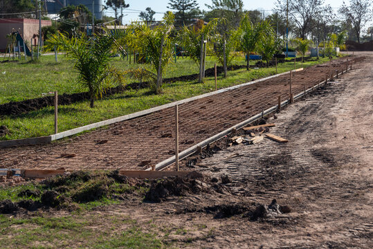 Wooden formwork and steel mesh reinforcement laid out for concrete path construction in park
