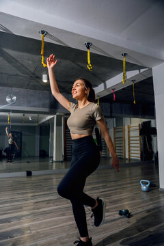 Young woman balancing on one leg with confidence. Sporty woman performing functional warmup in gym, fitness training concept.