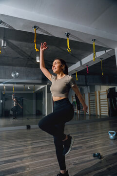 Fitness woman performing dynamic balance exercise with raised knee. Athletic woman strengthening coordination in modern gym, fitness concept.