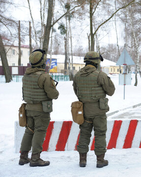 Armed Ukrainian soldiers in full uniform standing guard on military checkpoint on winter road