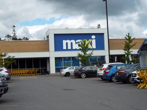 Gatineau, Quebec, Canada &ndash; June 13, 2026: A "Maxi supermarket" storefront with a prominent blue sign, large windows, and parked cars under an overcast sky at 545 Chem. Vanier.