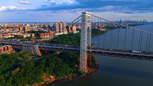 Beautiful green Hudson River waterfront with the George Washington Bridge. Lots of traffic on the bridge at sunset time. New York City, USA.