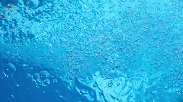 Small and large bubbles on the blue water surface. Random motion. Minimal. Copy space. 