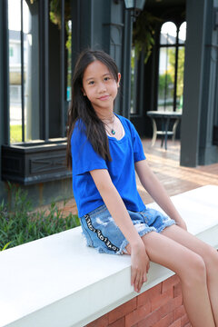 Smiling young Asian girl relax and sitting in park while looking camera.