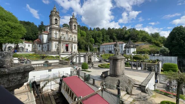 Scenic view of historic church and gardens in Braga Portugal, showcasing lush greenery, ornate architecture, and a funicular railway in a picturesque landscape under a bright blue sky