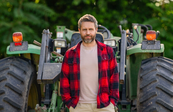 Farmer in field wear gum boots at tractor. Crop harvesting. Agriculture equipment. Farmer with harvesting machinery. Mature man at tractor. Crop inspection. Agriculture and field work