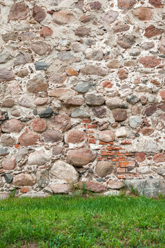 Old ancient brick stone wall background with green grass