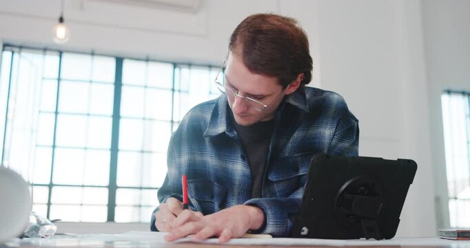 Architect, paper and man in office with writing, design plan and draft of renovation project. Review, tablet and engineer in agency with notes, progress checklist and strategy brief for remodeling.