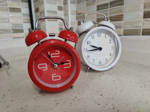 Two retro alarm clocks standing side by side symbolizing time management, urgency, passing of moments, deadlines, balance between work and life, dual choices, countdown, schedule planning, and routine
