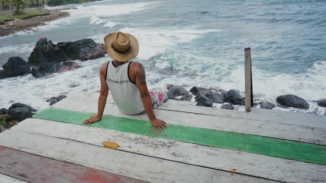 Latino Caribbean man wearing a straw hat, sitting by the Caribbean Sea in Capurgan&aacute;, Choc&oacute;, Colombia.