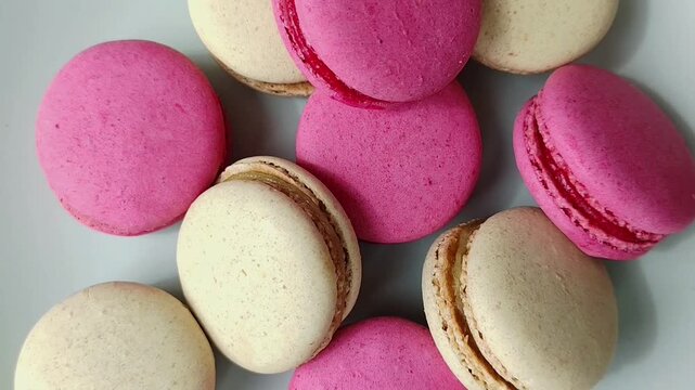 Close up of pink and vanilla macarons on a white surface in studio light. Sweet dessert, bakery, food styling, minimal.