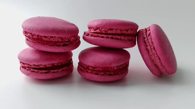 Stack of pink macarons on a white surface in a studio with soft light. Sweet dessert, bakery, food styling, minimal.