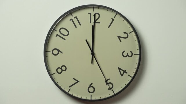 Modern wall clock time lapse. Wall clock showing 12 o'clock on a white wall. Running time pointers.