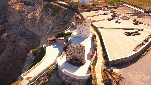Aerial drone view over cliffside windmill venue at Heart of Santorini with caldera panoramic view. Santorini, Greece.