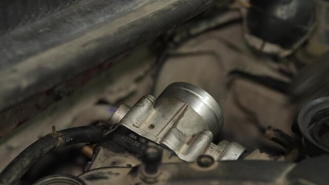 Mechanic installing air intake hose onto car throttle body assembly.