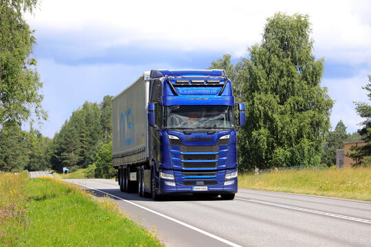 Blue Scania semi truck hauling an NCS freight trailer on the highway on a sunny summer day. Copy space.