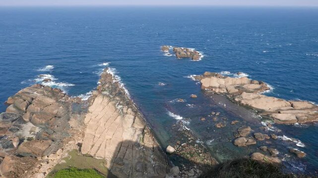 Rocky shelf from above, bird's eye view from cliff height. Yehliu Geopark, popular sightseeing place in Taiwan. Stunning East China Sea bluish water colour, impressive cliff and reef near shore.