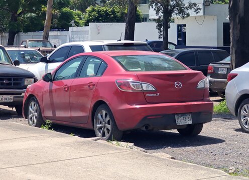 ZAPOPAN, MEXICO - AUGUST 5, 2026: Red Mazda 3 sedan parked in street parking lot.