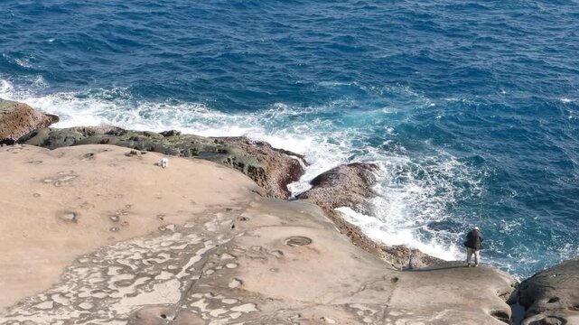 Little fisherman figure on massive smooth eroded rocky shore, Yehliu Geopark, Taiwan. Natural colour and impressive rocks of Yeh-Liou cape end point. Yeh-Liou is cape on north coast of Taiwan