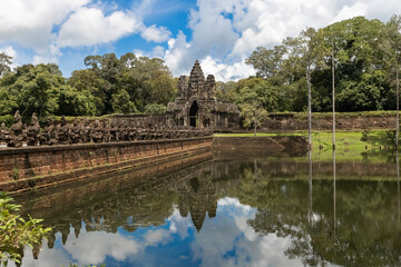 Fototapeta premium South Gate of Angkor Thom with its iconic stone causeway, ancient guardian statues and reflection in the moat, Siem Reap, Cambodia