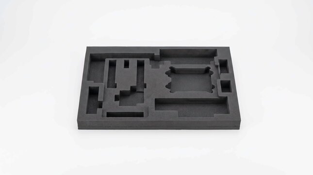Black protective foam insert with precise cutouts for electronic equipment packaging on a white studio background