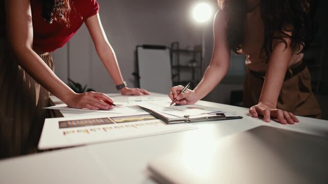 Two young businesswomen colleagues working together in a modern office. They are discussing and checking financial data on documents