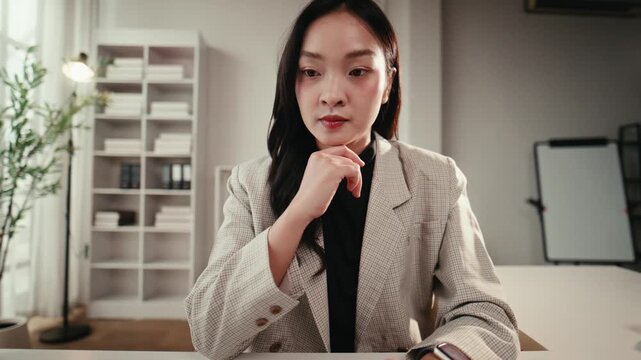 Focused young asian business woman using laptop computer at her desk. Professional creative manager working on a project in a modern office