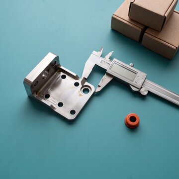 Digital caliper measuring machined metal bracket from above