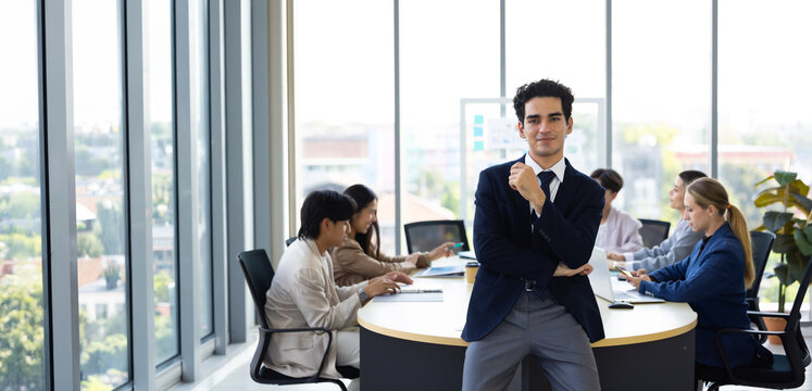 Businessman Standing In Corporate Office. working in office workplace. Young middle-aged Hispanic smiling handsome businessman entrepreneur looking at camera