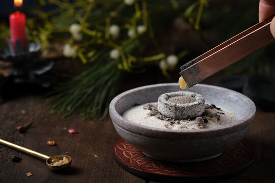Incense ritual on Yule - placing frankincense with tongs on a glowing incense charcoal