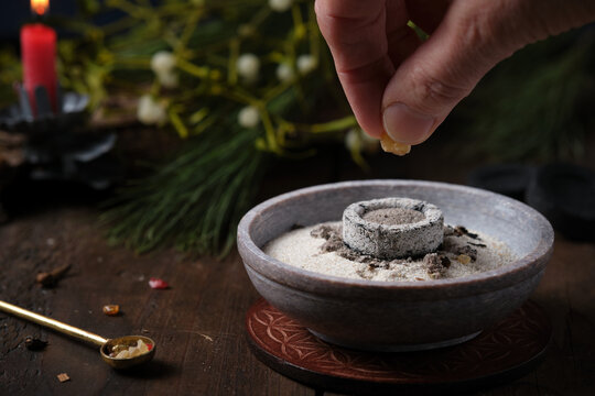 Incense ritual on Yule - placing frankincense by hand on a glowing incense charcoal