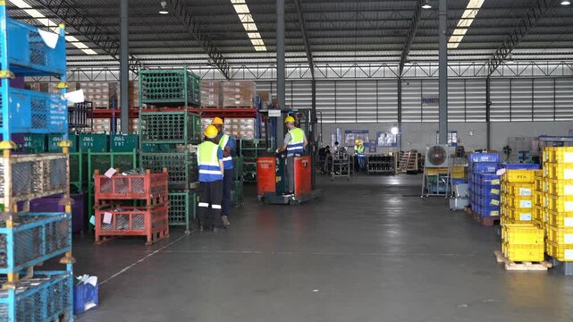 Workers move boxes in a warehouse during regular hours in an industrial setting