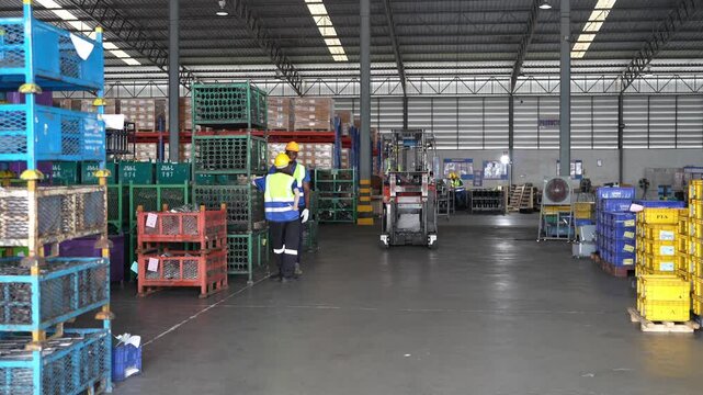 Workers move crates in a large warehouse during the day