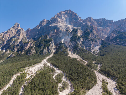 Aerial view of a mountain slope in the Dolomites showing signs of a recent landslide and debris flow with rocky terrain and pine forests in Cortina d'Ampezzo, Veneto, Italy.